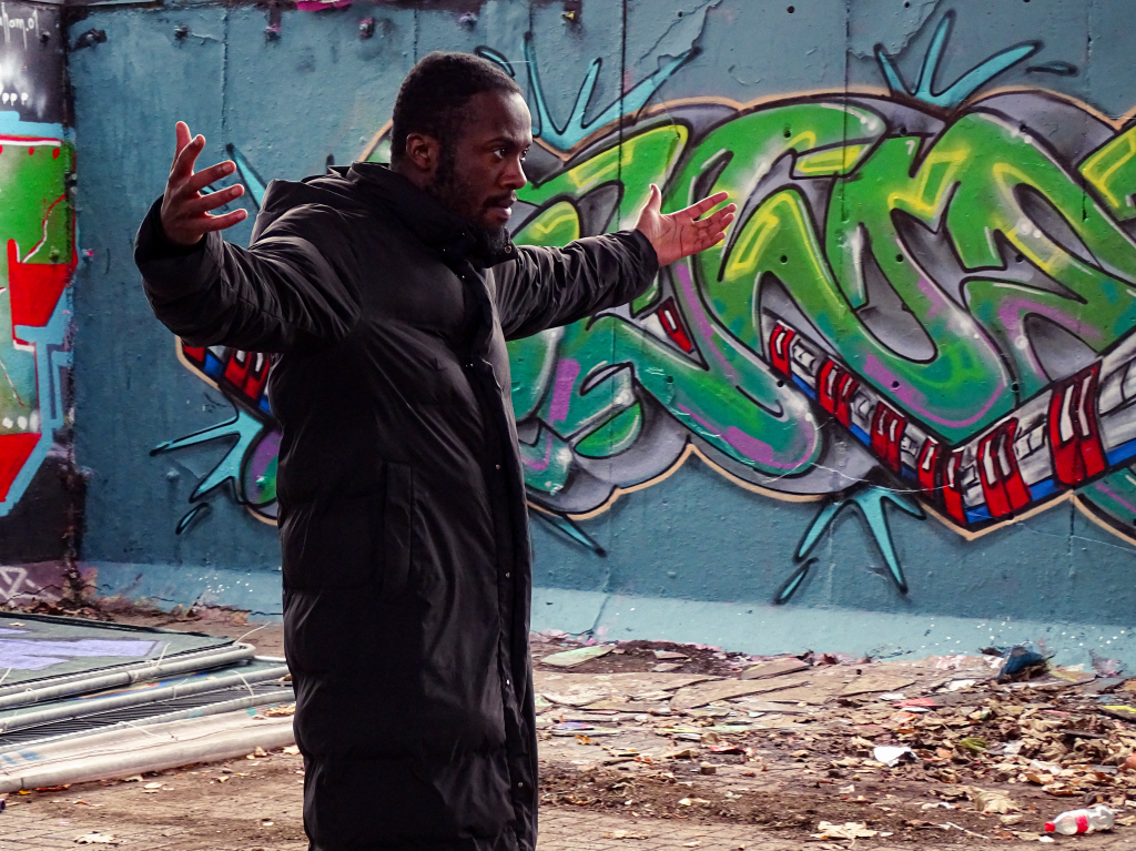 Actor filming a take with his arms raised.
