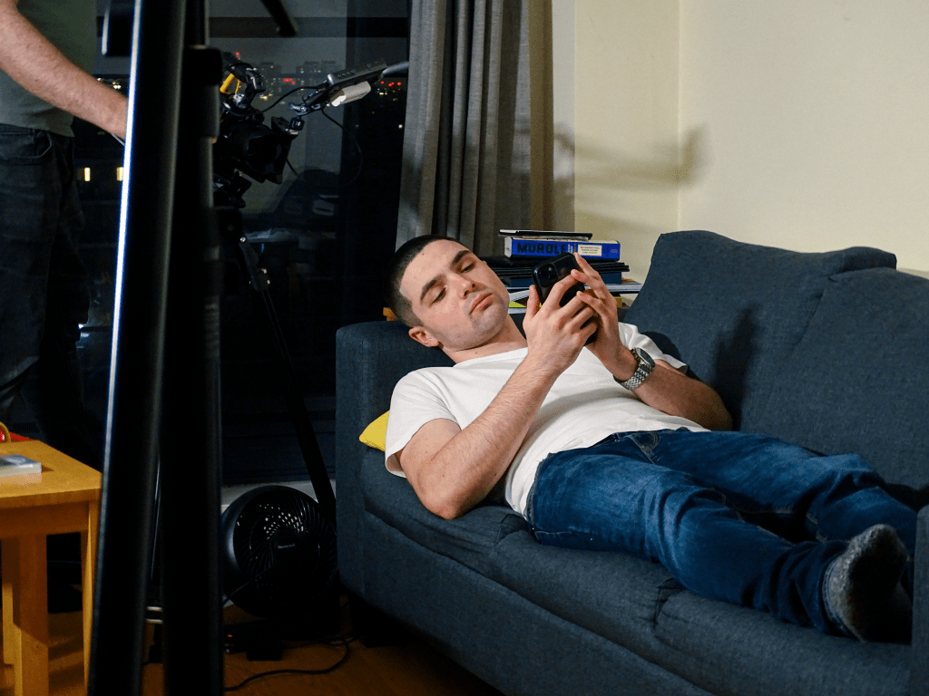 Actor filming a take lying on couch with his phone.