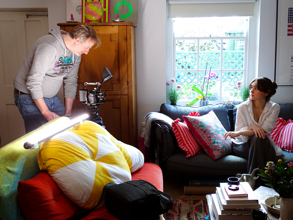 Director filming actor sitting on couch.