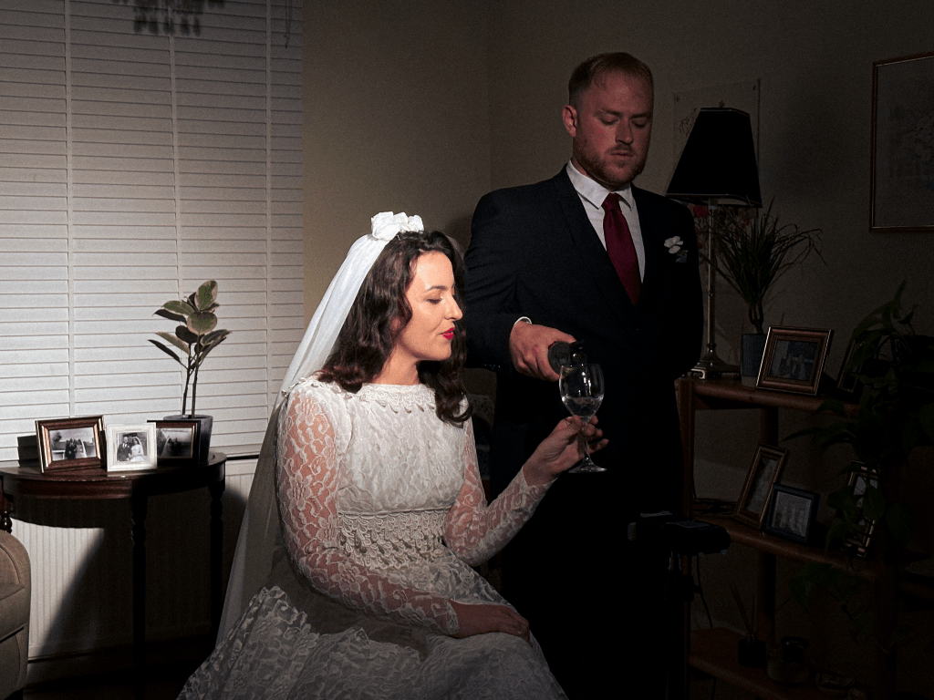 Actor pouring wine in other actor's glass.